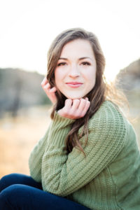 close up of senior girl wearing a green sweater not smiling her chin resting in her hands