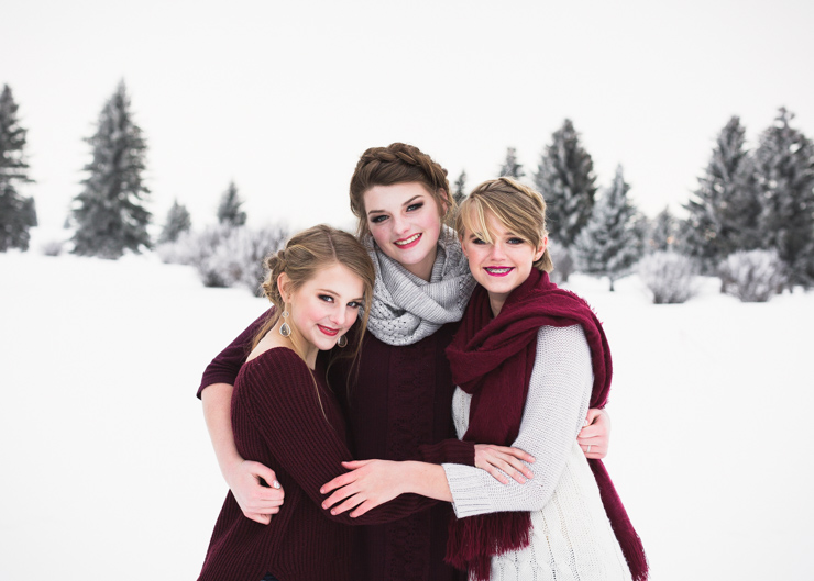 three senior girls smiling and standing with arms around each other in the snow