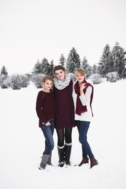three senior girls wearing maroon stand next to each other in the snow