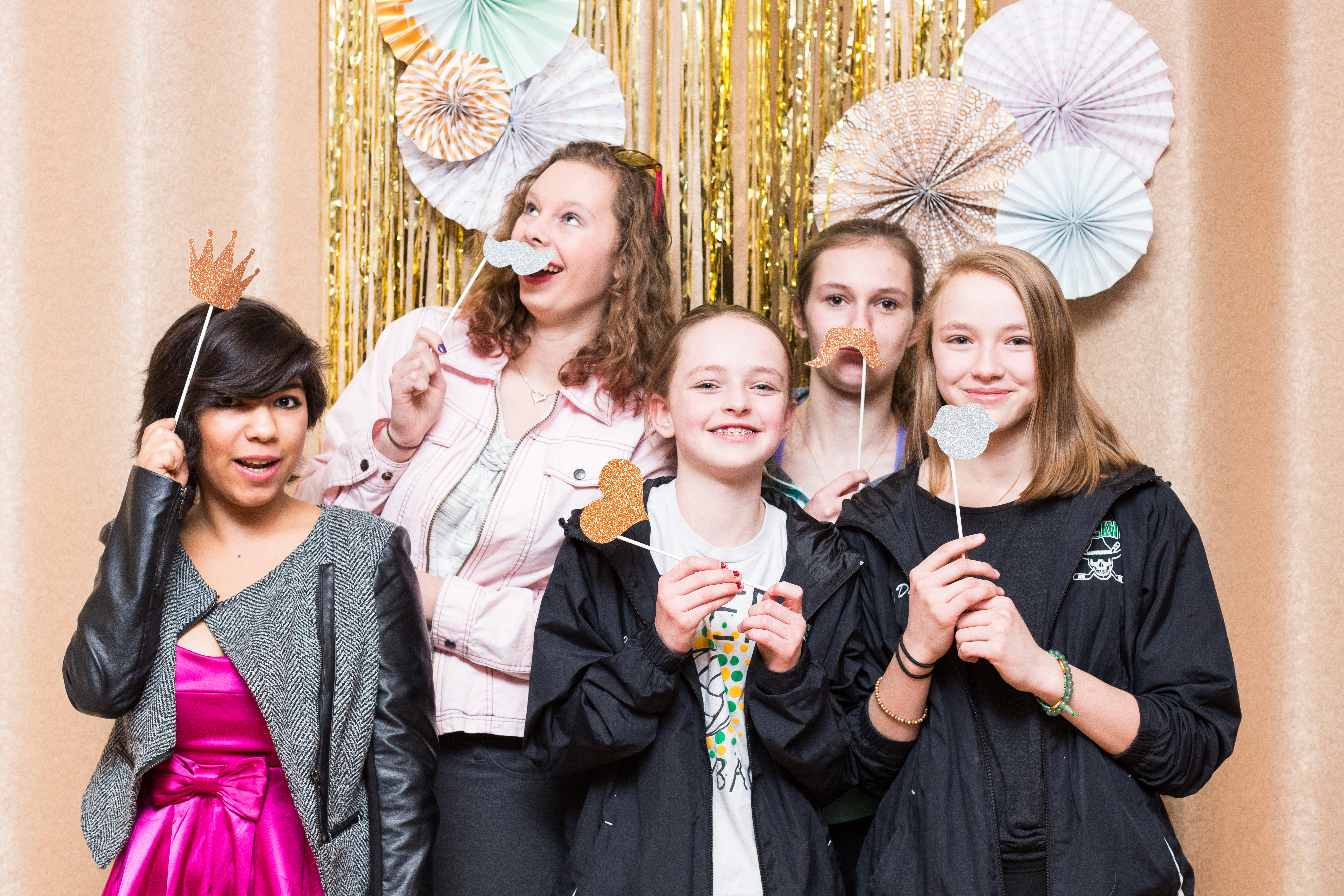 Group of five girls holding props and smiling in the photobooth at Little Birds Photography's Glitter & Glam Night