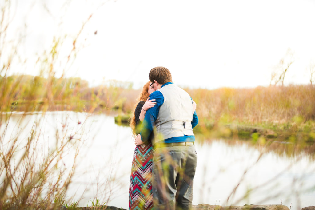 couple kisses after a successful proposal on the bank of a river