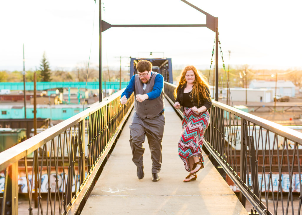 Couple dances side by side on a bridge crossing the railroad tracks