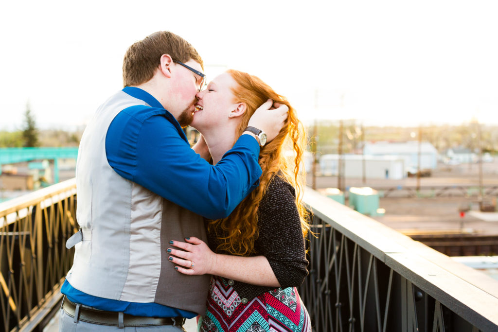 Couple kisses while man runs his hand through the woman's long curly red hair