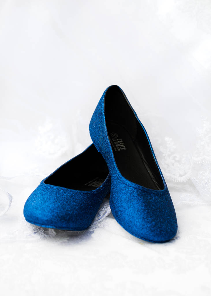 a pair of royal blue sparkly flats rest on the veil