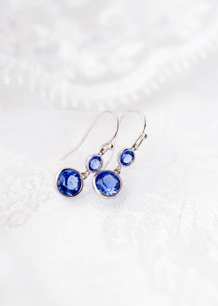 simple royal blue crystal earrings lay on the bride's veil