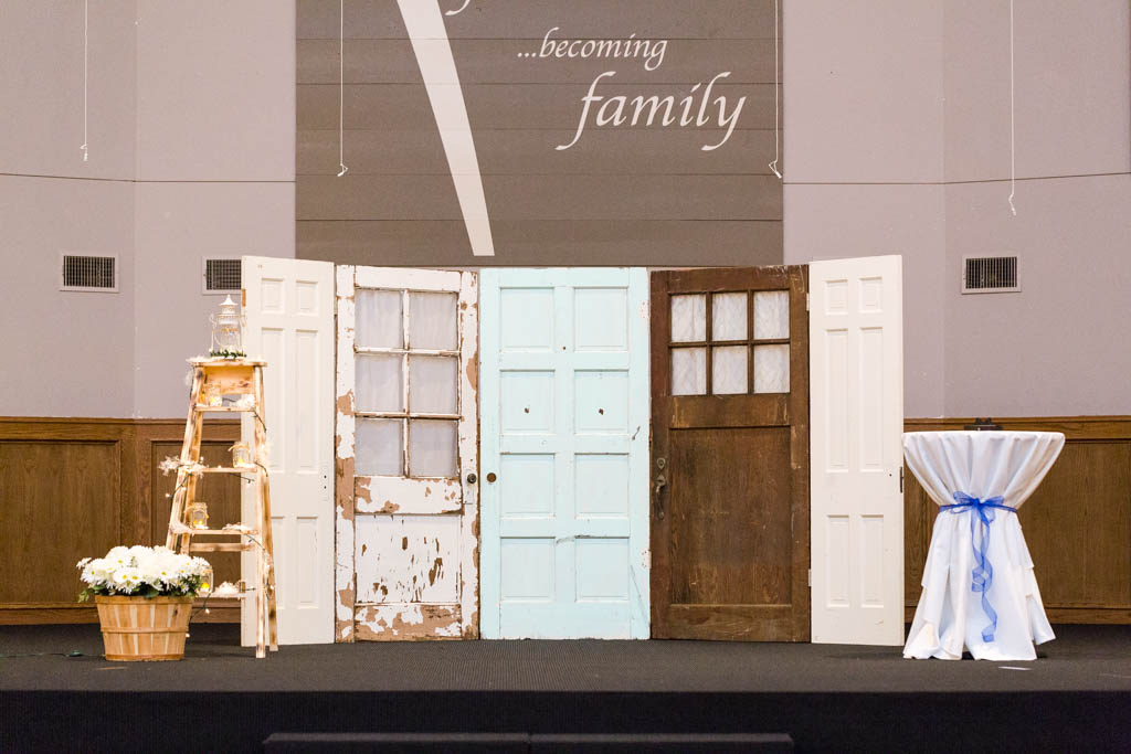 a ceremony backdrop made from a collection of vintage doors that are painted white, blue and brown