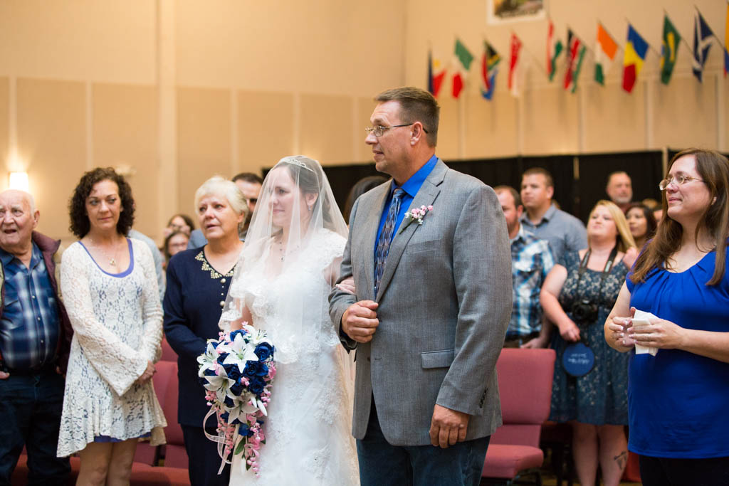 bride and her father stand at the front of the aisle before he gives her away