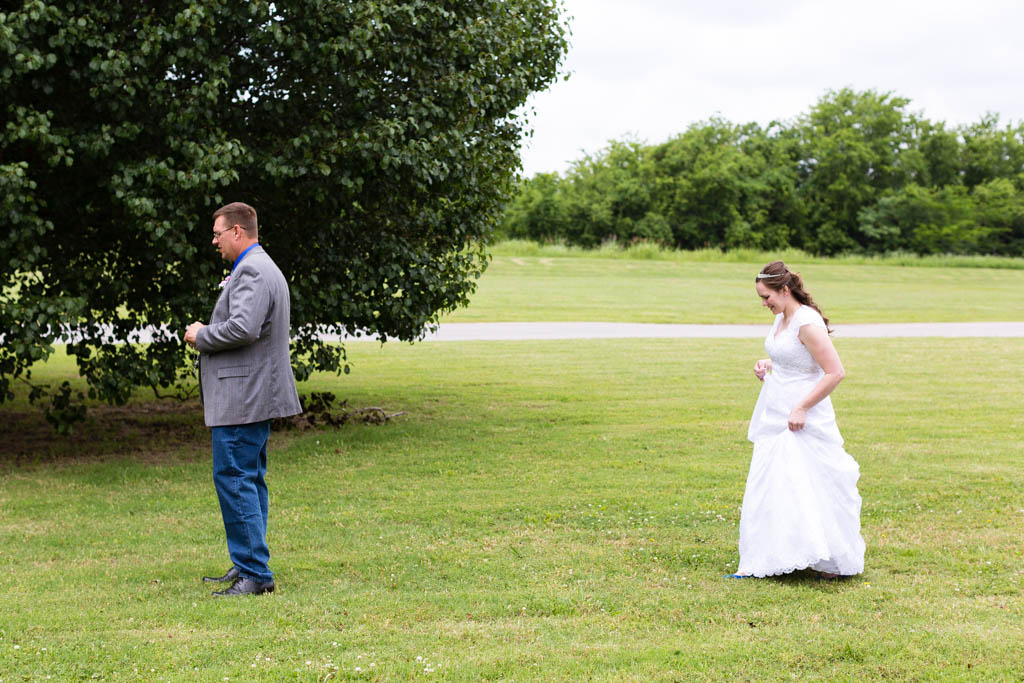 brides walks through the grass for a first look with her dad before the ceremony
