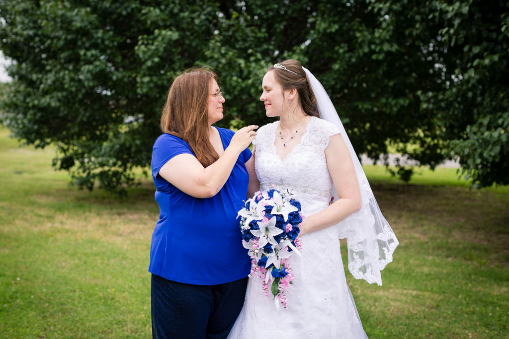 the mother of the bride shares a quiet moment with the bride in the grass before portraits are taken