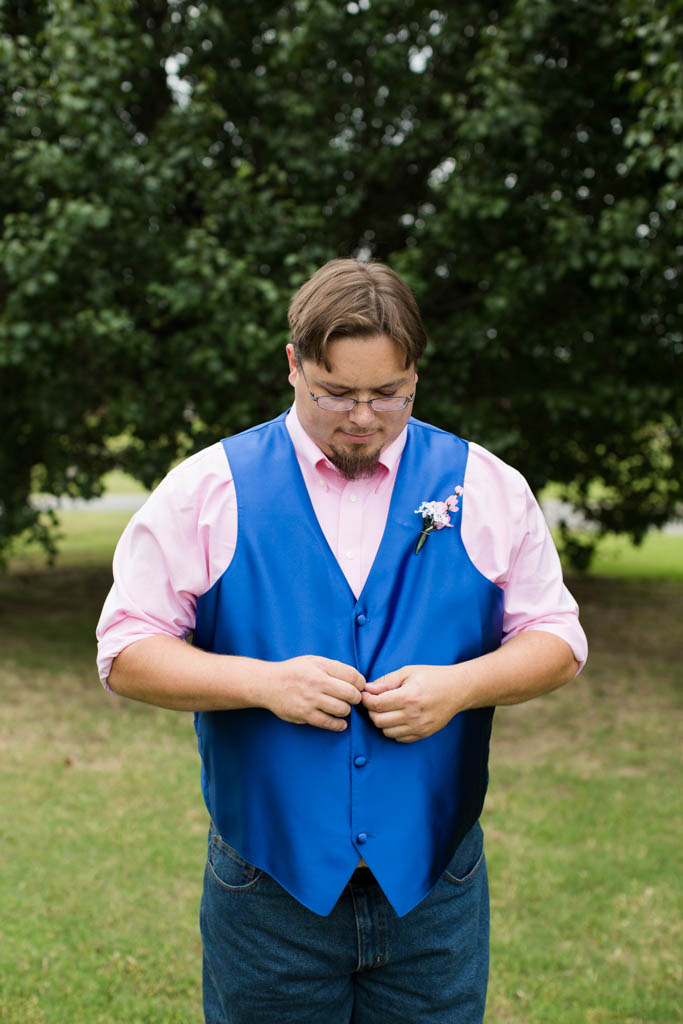 groom adjusts his royal blue vest
