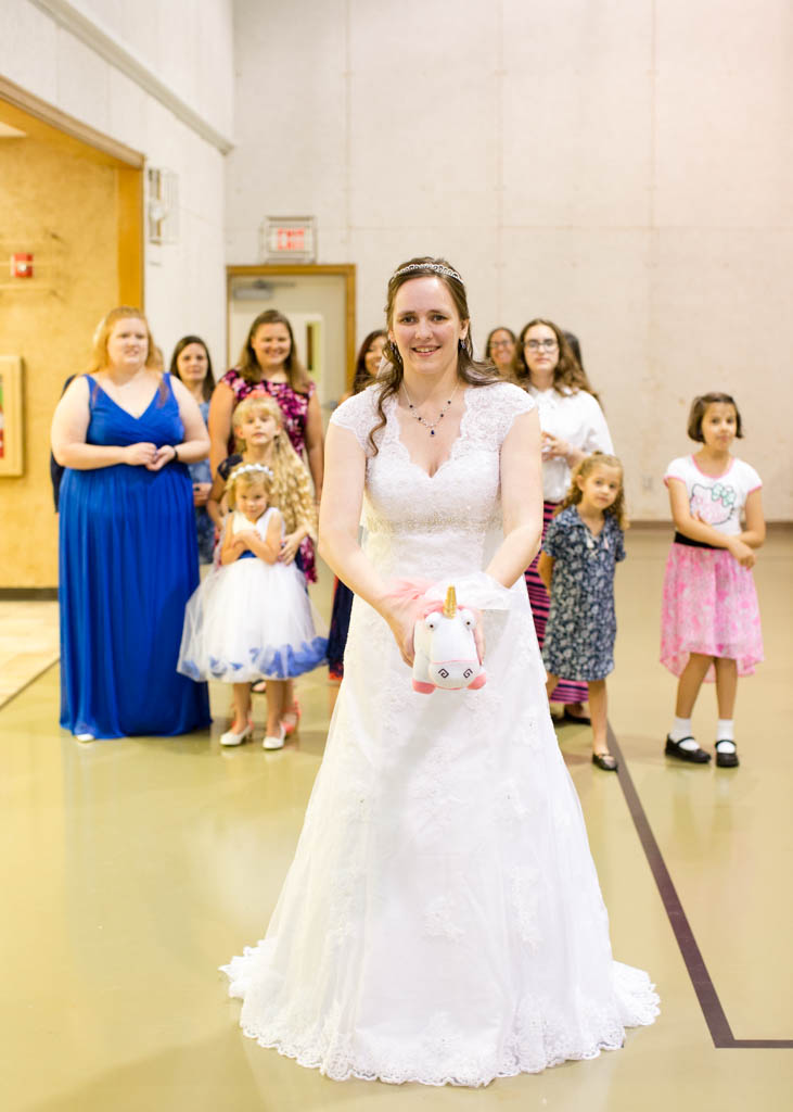 bride smiles before sh tosses stuffed pink and white unicorn to the single ladies at the reception