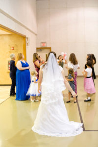 bride turns around and watches as the single ladies try to catch the stuffed pink and white unicorn that she tossed