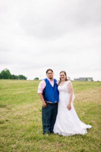 bride and groom stand side by side in a field