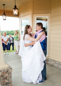 bride and groom enjoy their first dance on the front porch as guests look on