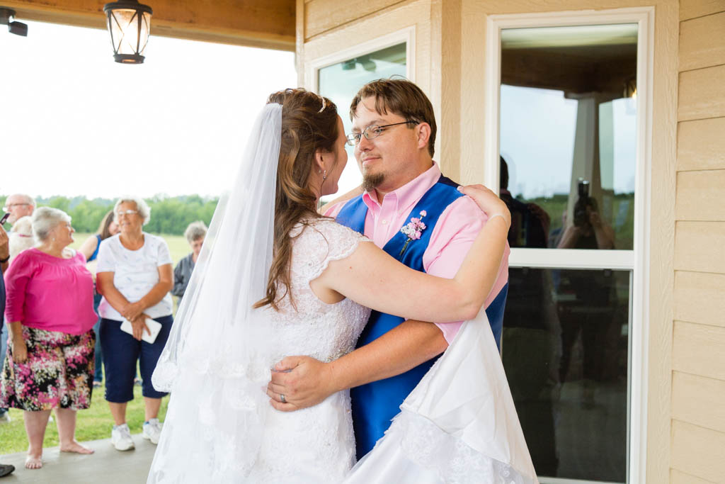 groom looks affectionately at his bride during their first dance while guests watch