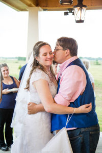 Groom kisses his bride on the cheek during their first dance