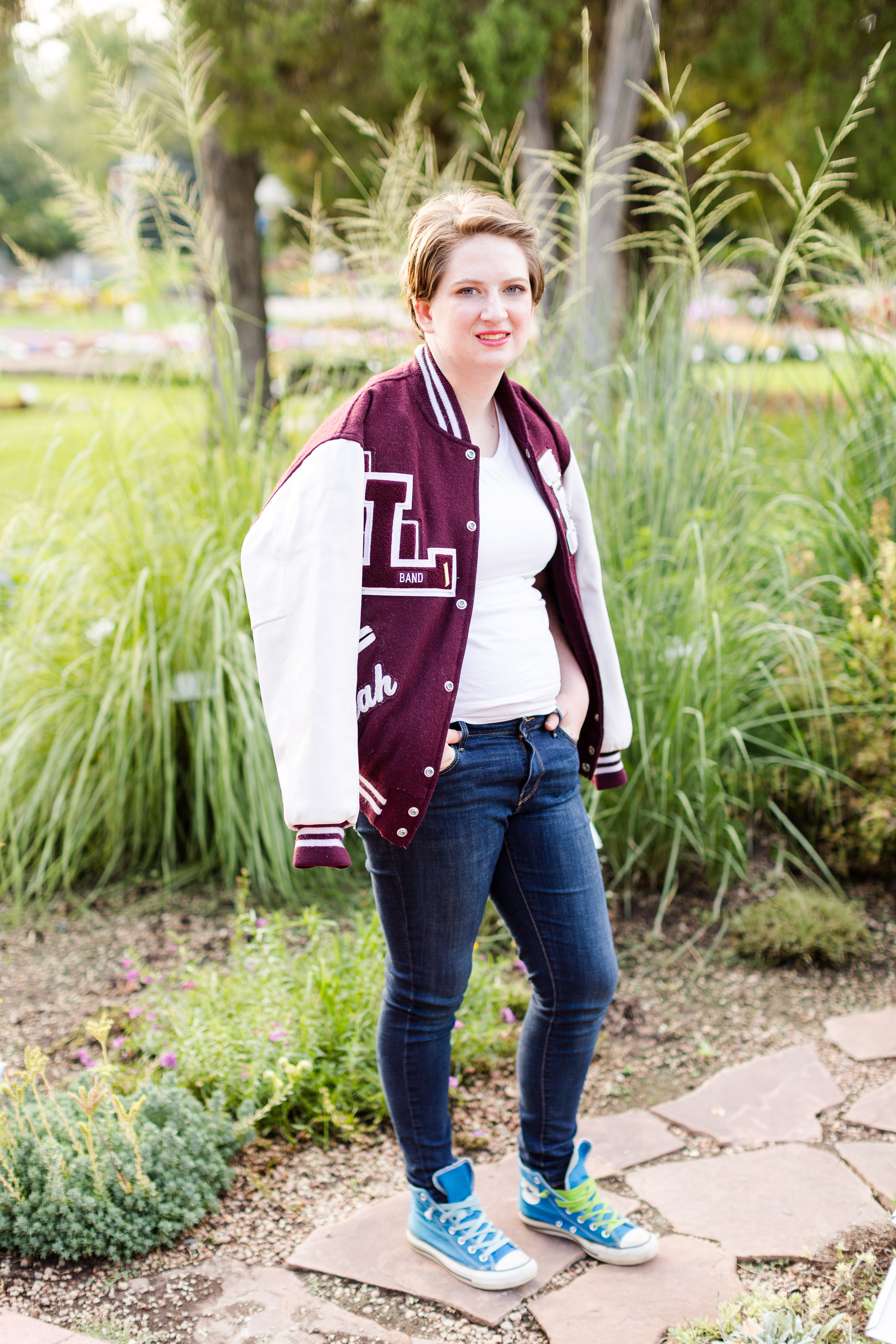 Senior girl wearing stands with her maroon and white letterman jacket draped over her shoulders