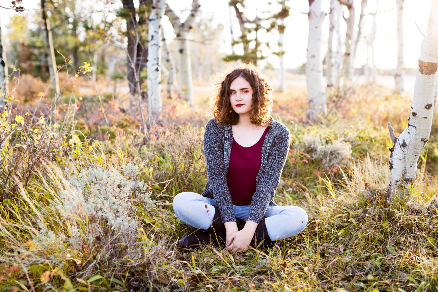 senior girl sitting cross legged in tall grass