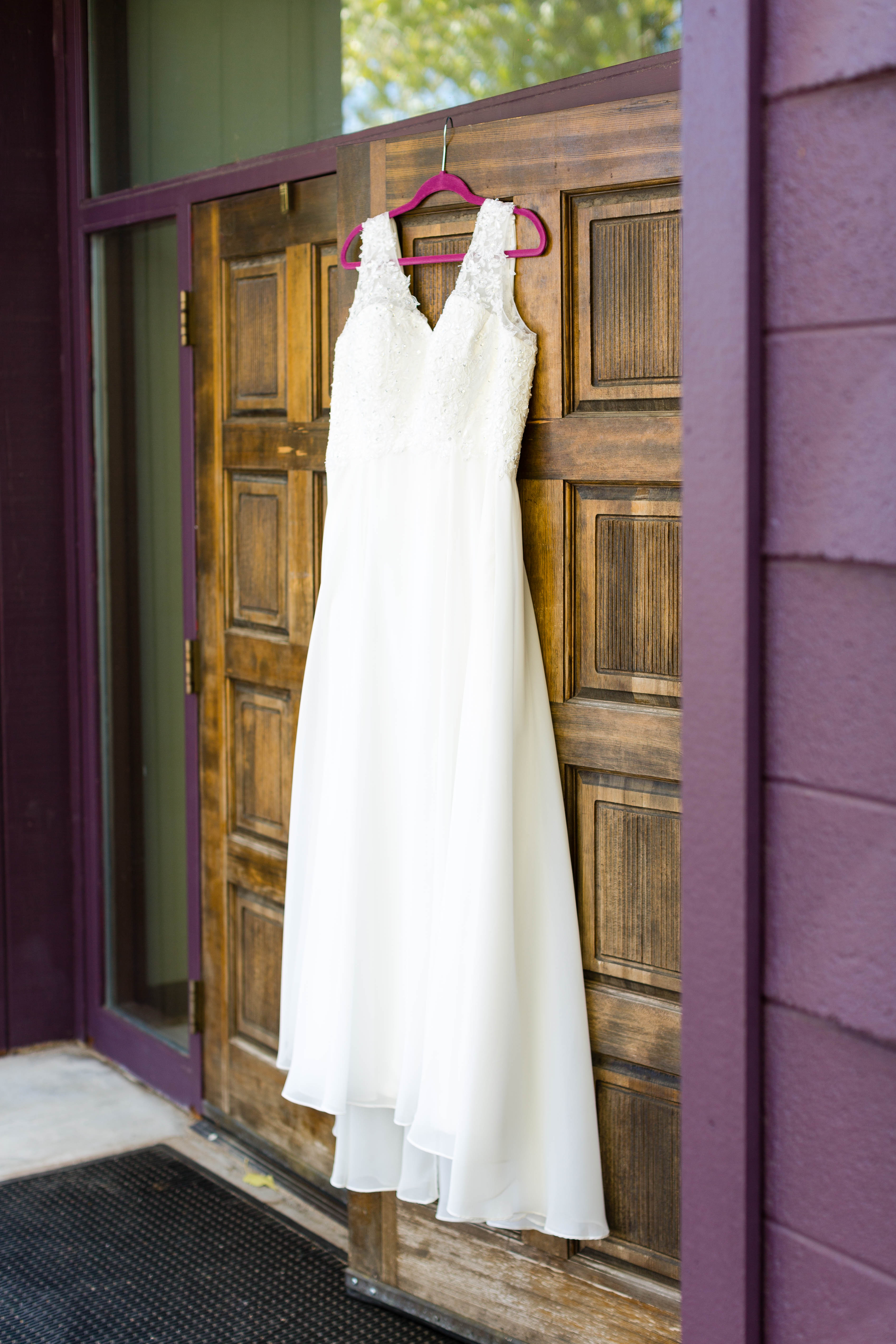 beaded lace wedding dress hanging from carved wooden doors