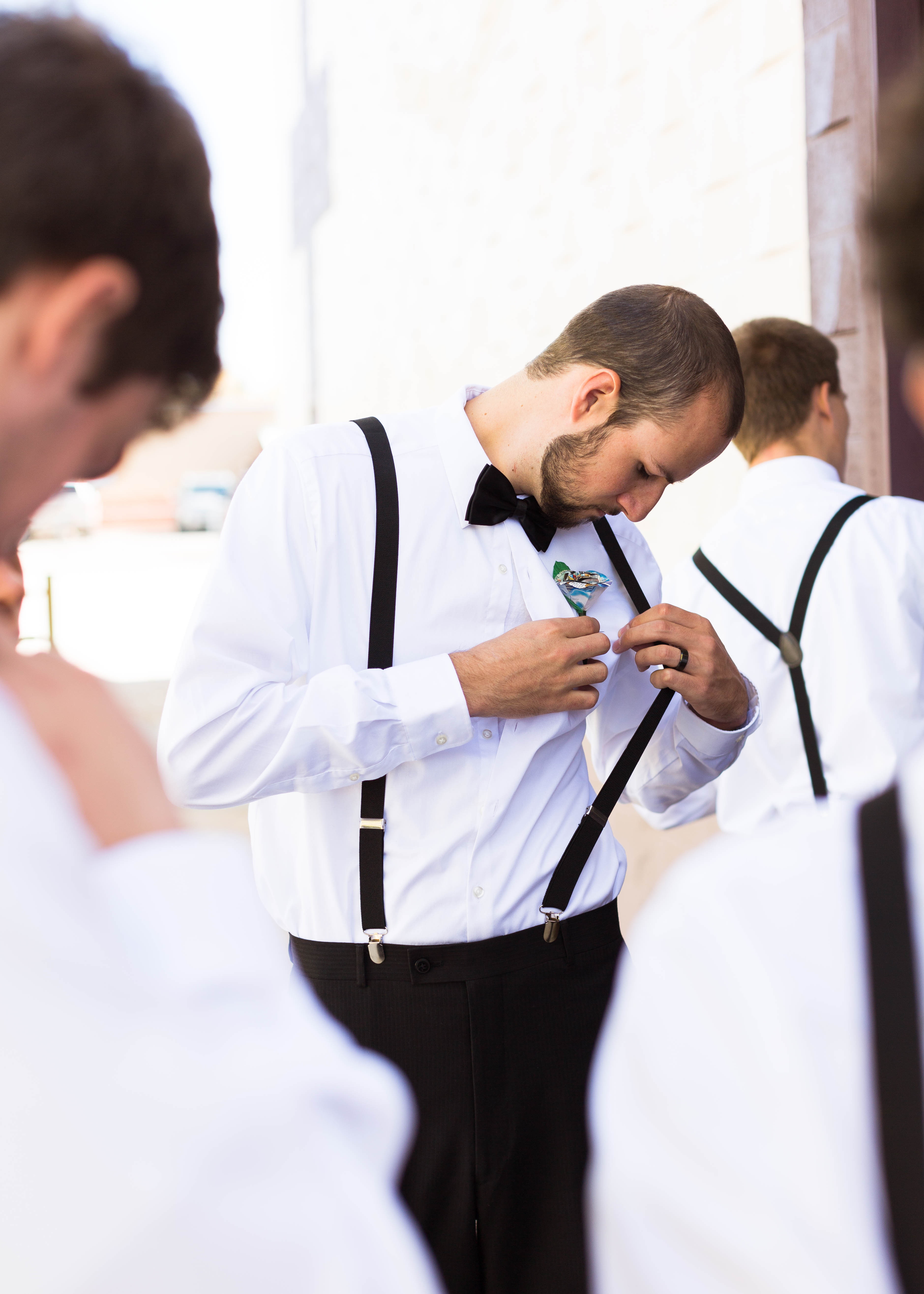 groomsmen focuses as his puts on his boutonniere