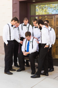 groomsmen gather around groom and pray for him outside of the church