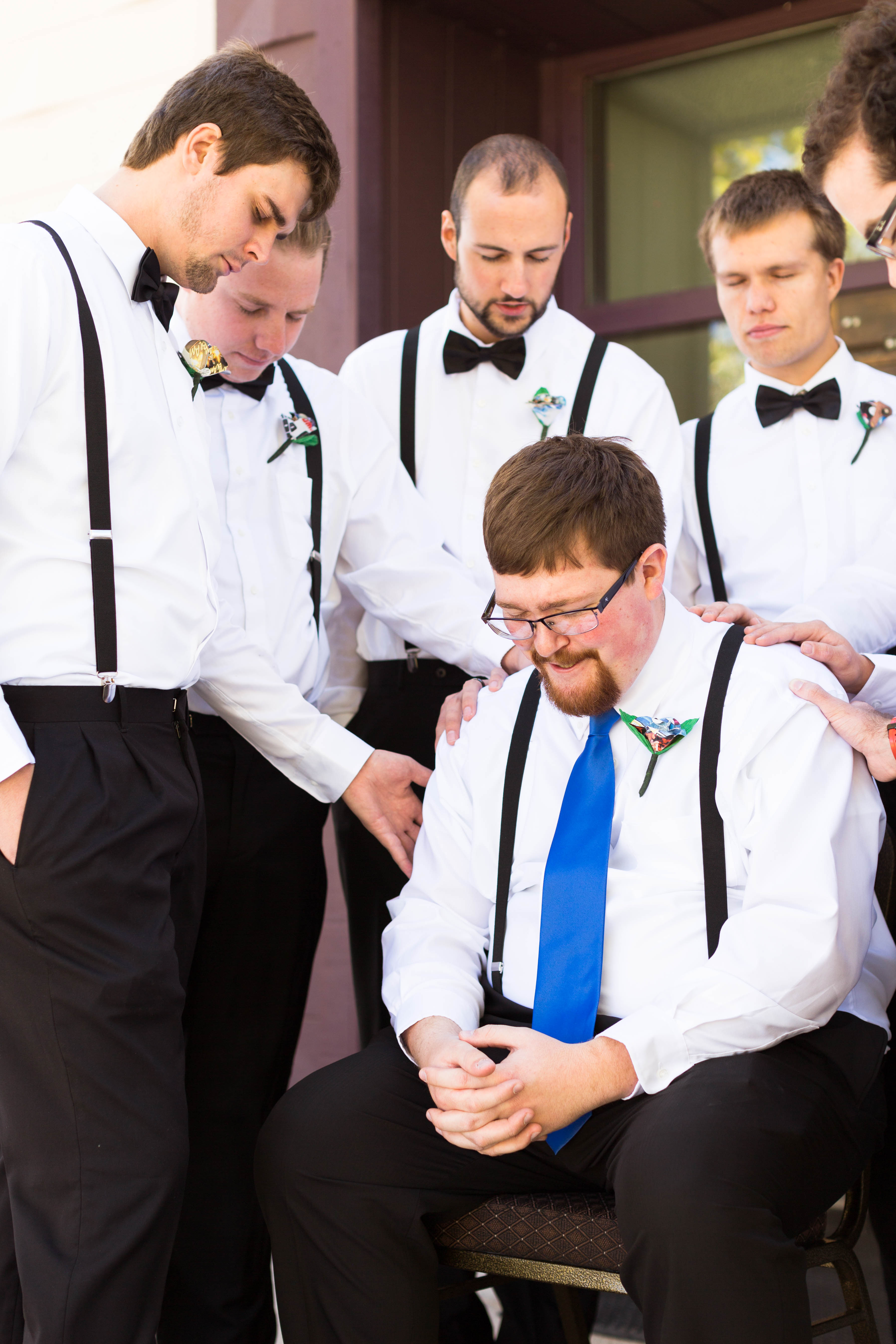 groomsmen surround groom and pray for him
