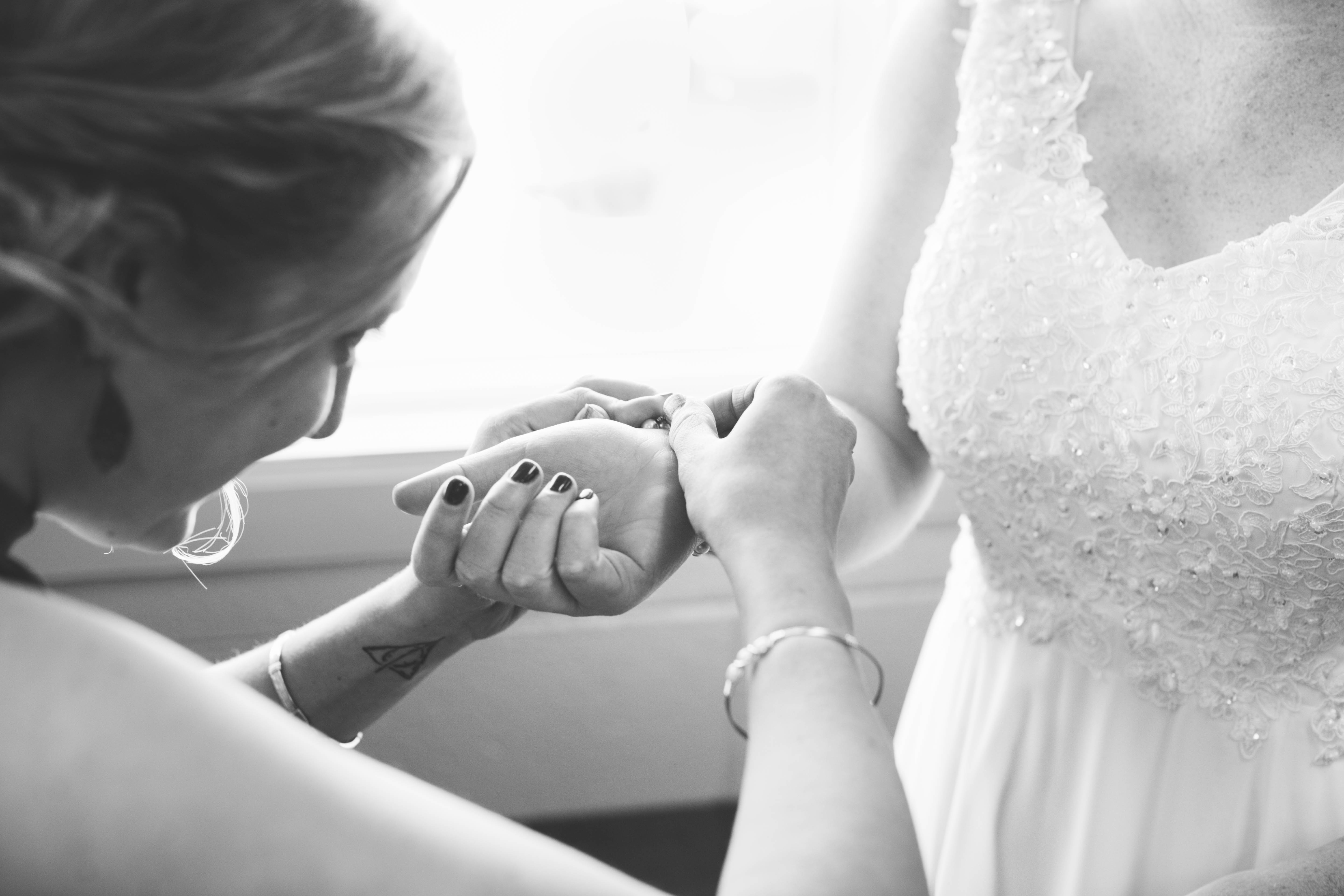 bridesmaid helps bride put on her bracelet