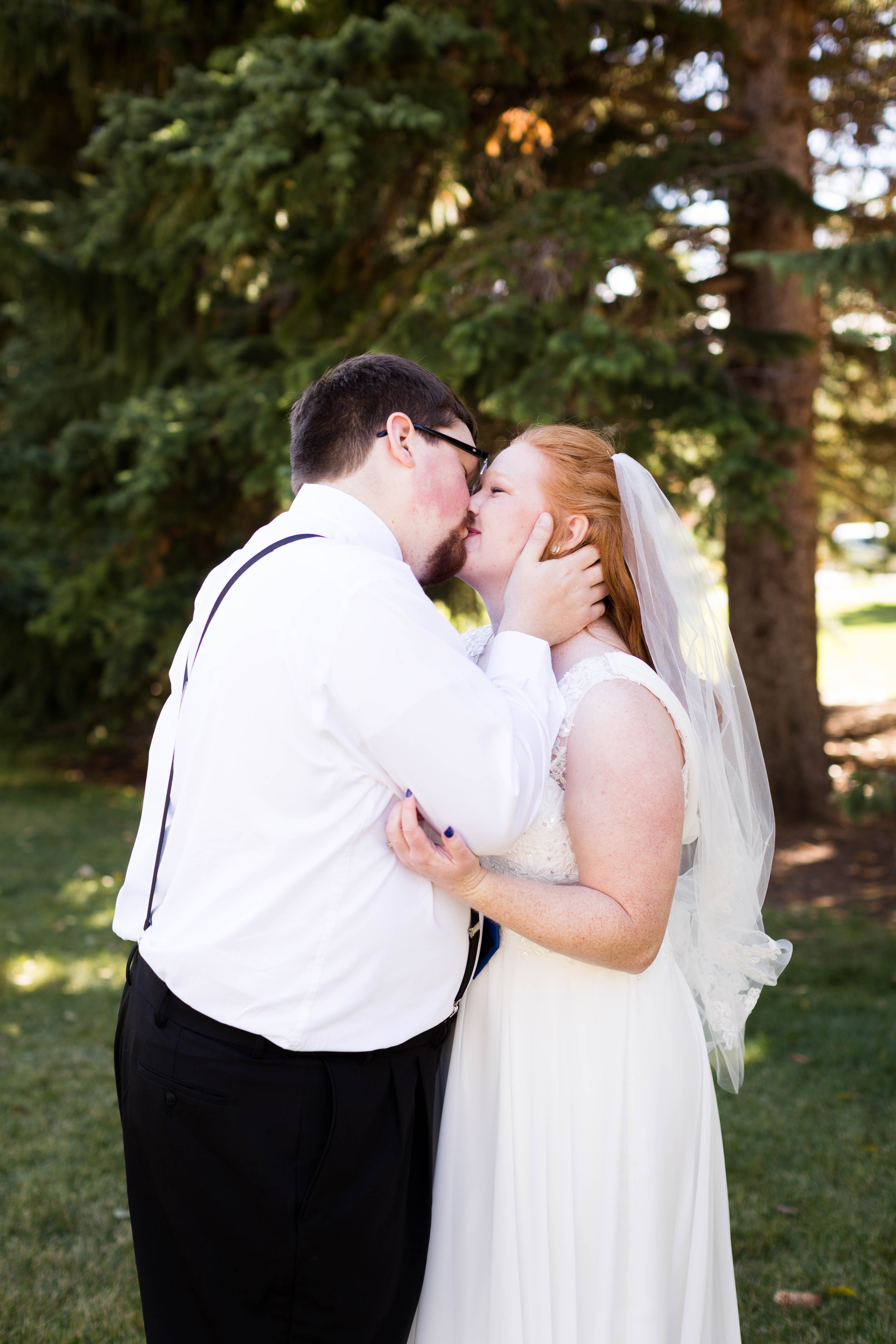 bride and groom share a kiss in the park