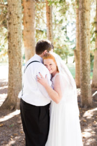 bride embraces her groom amongst pine trees