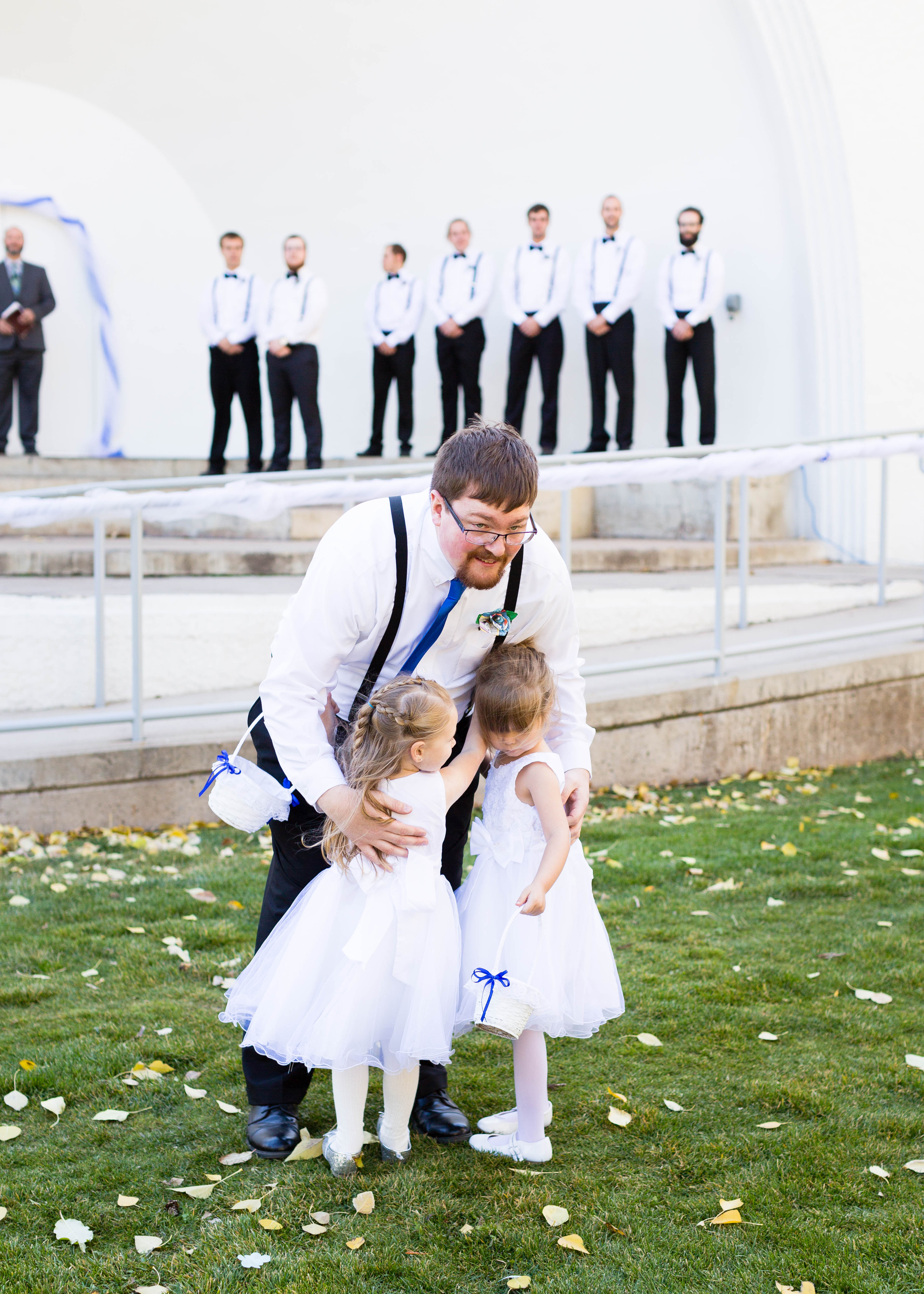 groom hugs flower girls after they walk down the aisle