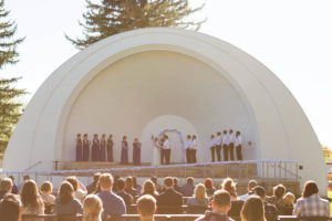 sun shines over park amphitheater as guests witness wedding ceremony
