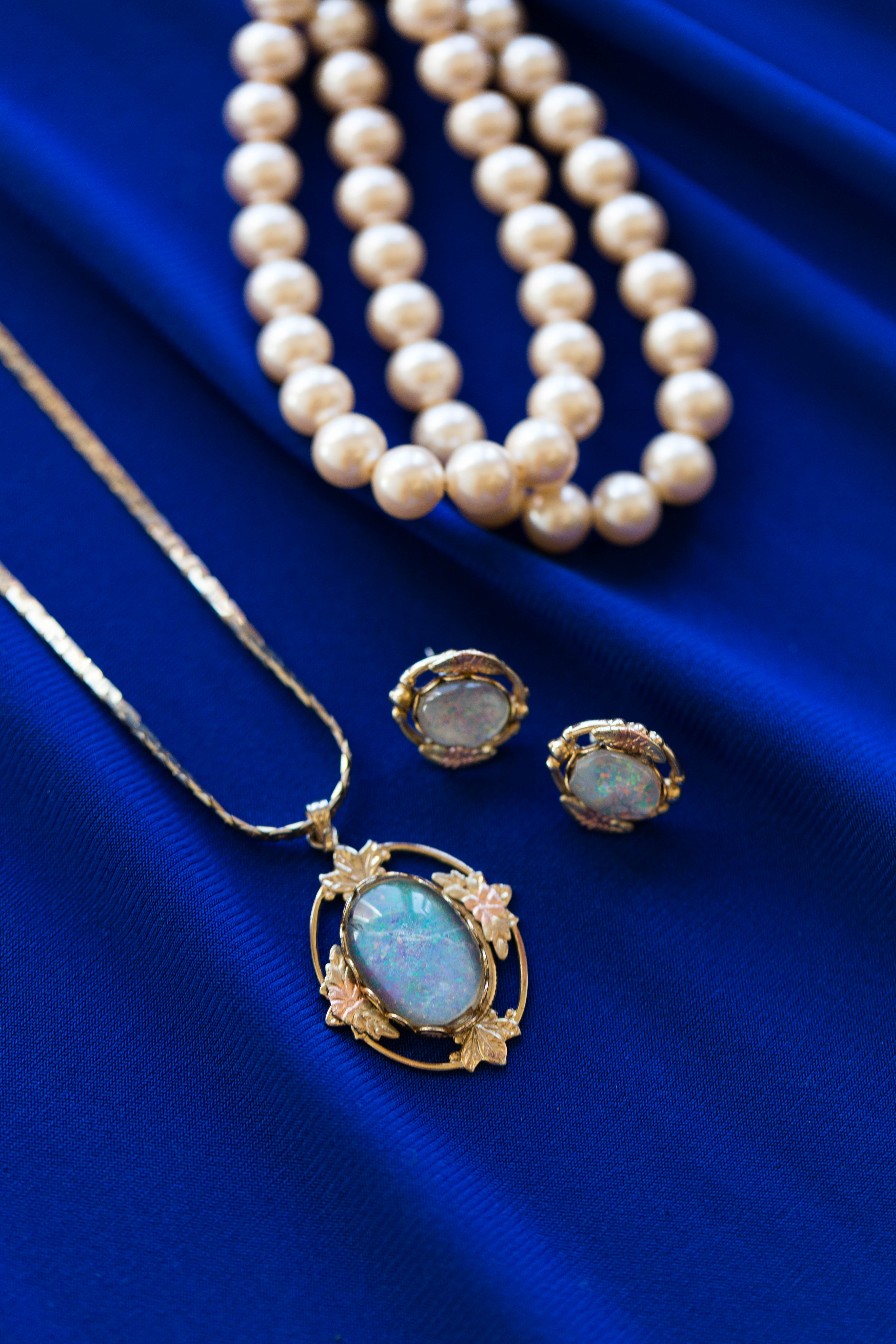 closeup of bride's gold and opal pendant earrings and necklace and pearl bracelet