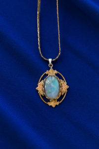opal and gold pendant necklace laying on blue bridesmaid dress