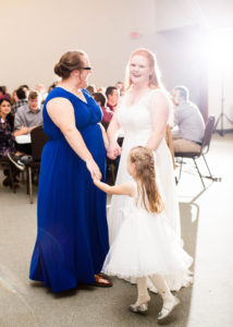 Bride dancing and holding hands with one of her bridesmaids and flower girls