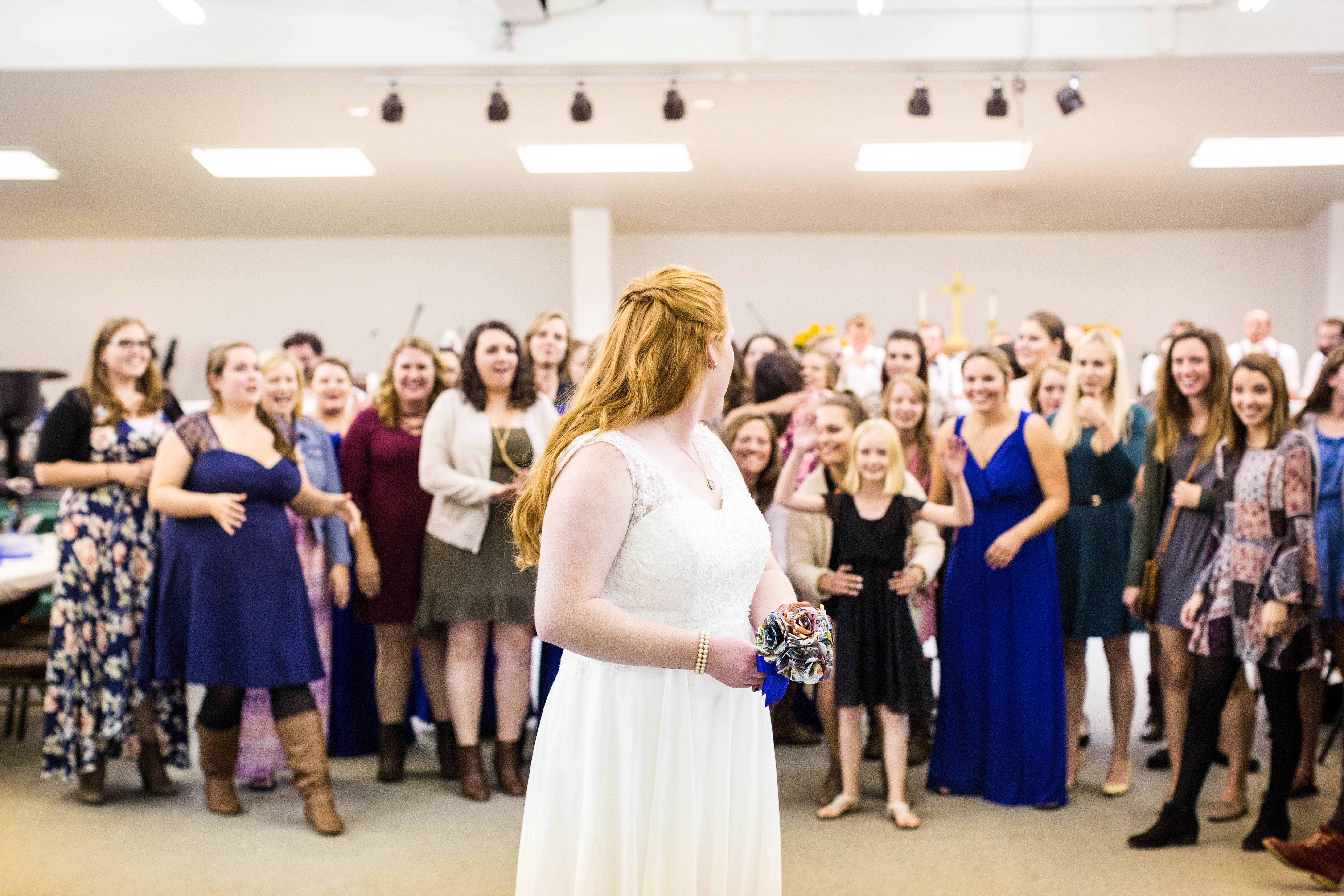 bride turns to look at the group of women behind her before she tosses the bouquet