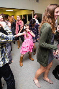 young girl wearing ruffled pink dress strikes a pose in the middle of the dance floor