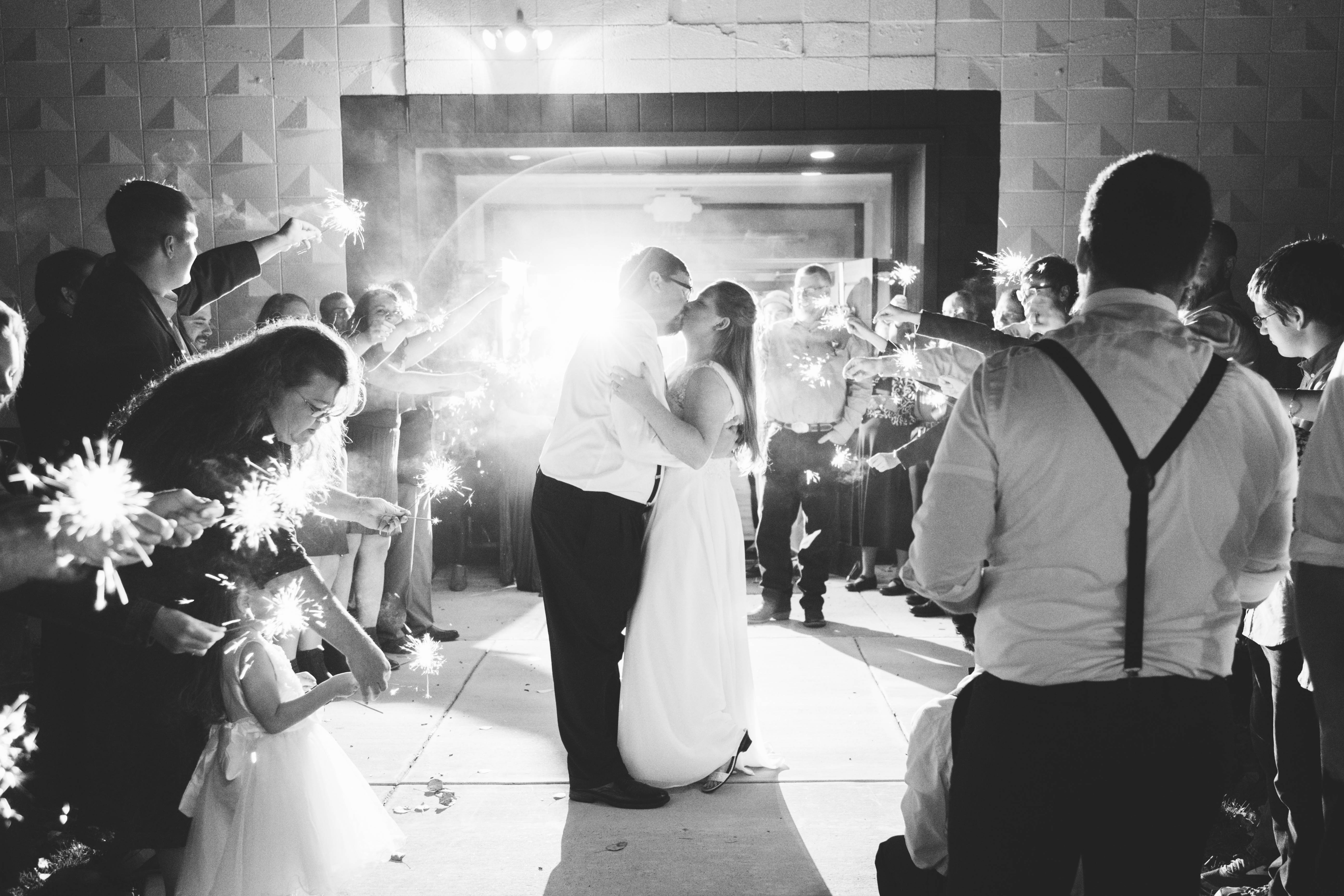bride and groom kiss as guests surround them with sparklers