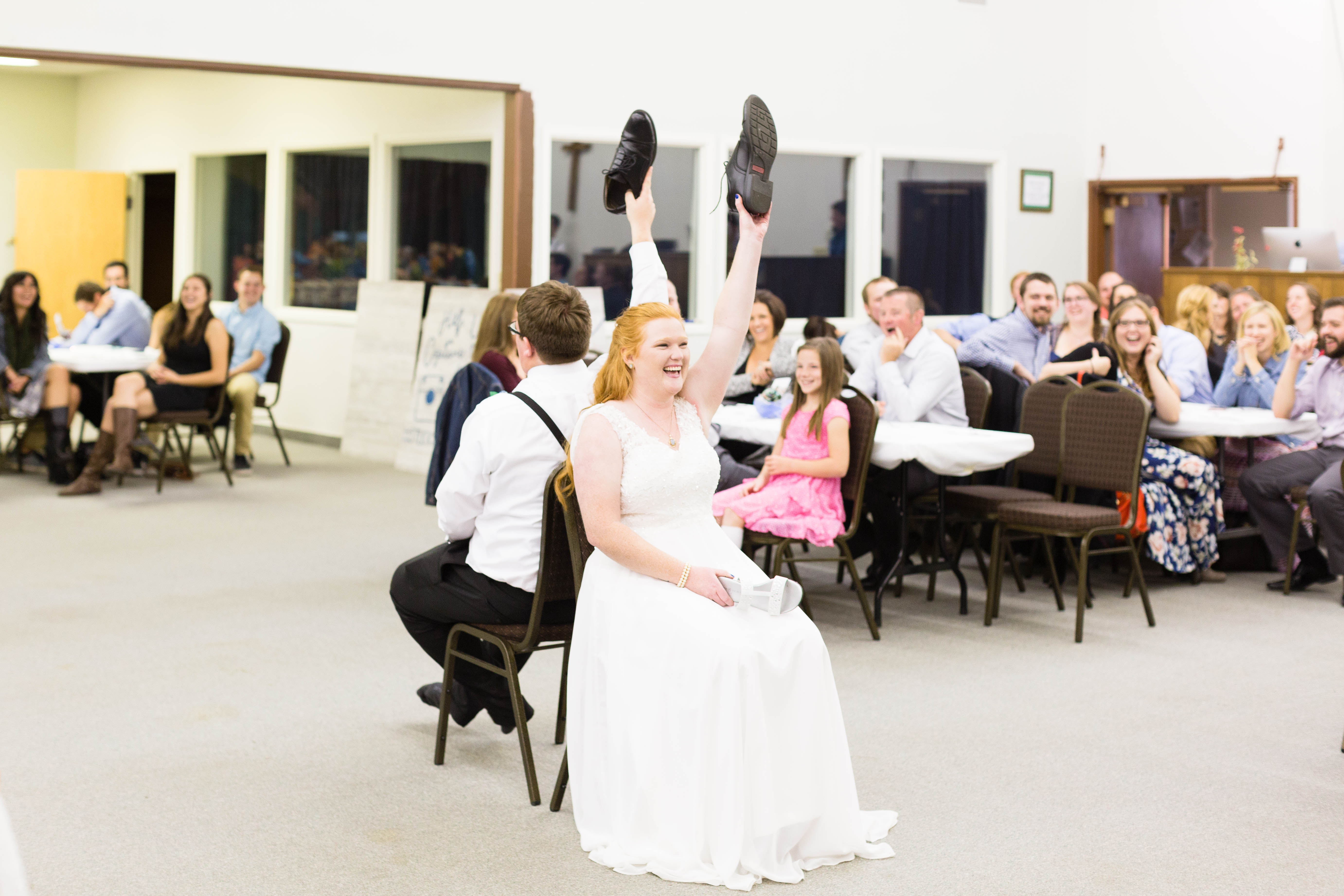 bride and groom laugh and hold up shoes while they play the Newlywed Game