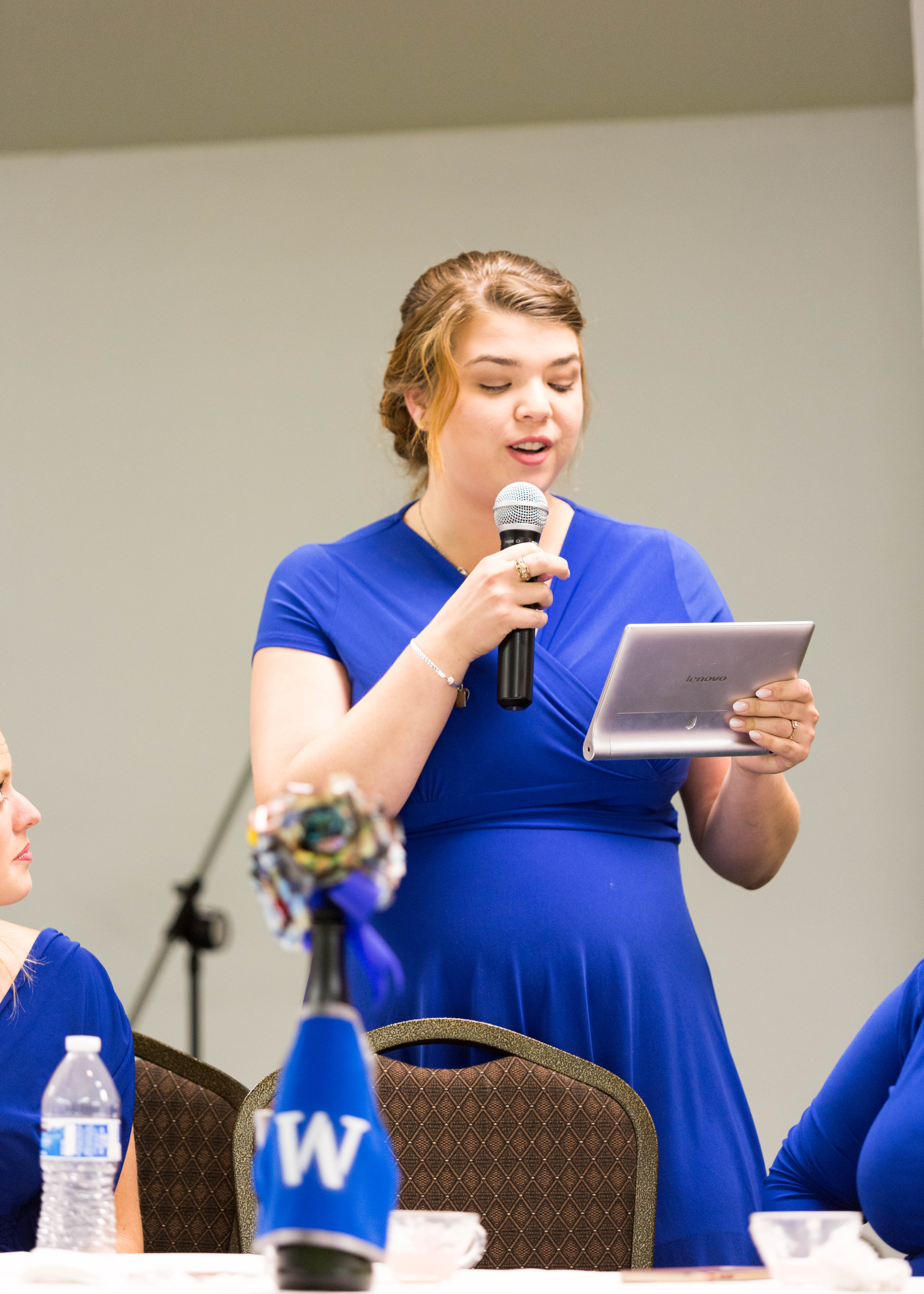 maid of honor in royal blue dress reads from notes during her speech