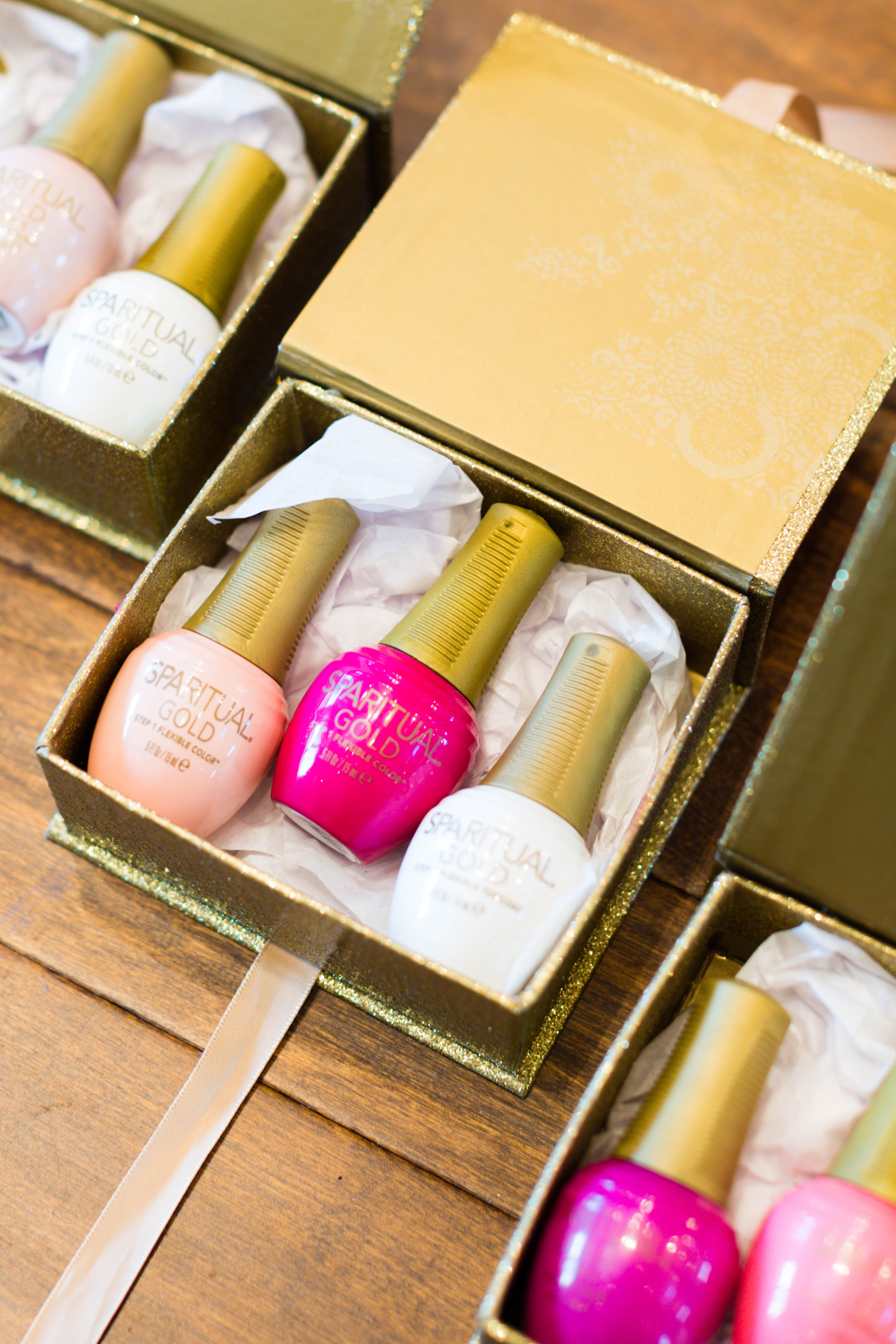 bottles of pink and white nail polish in glittery gold boxes