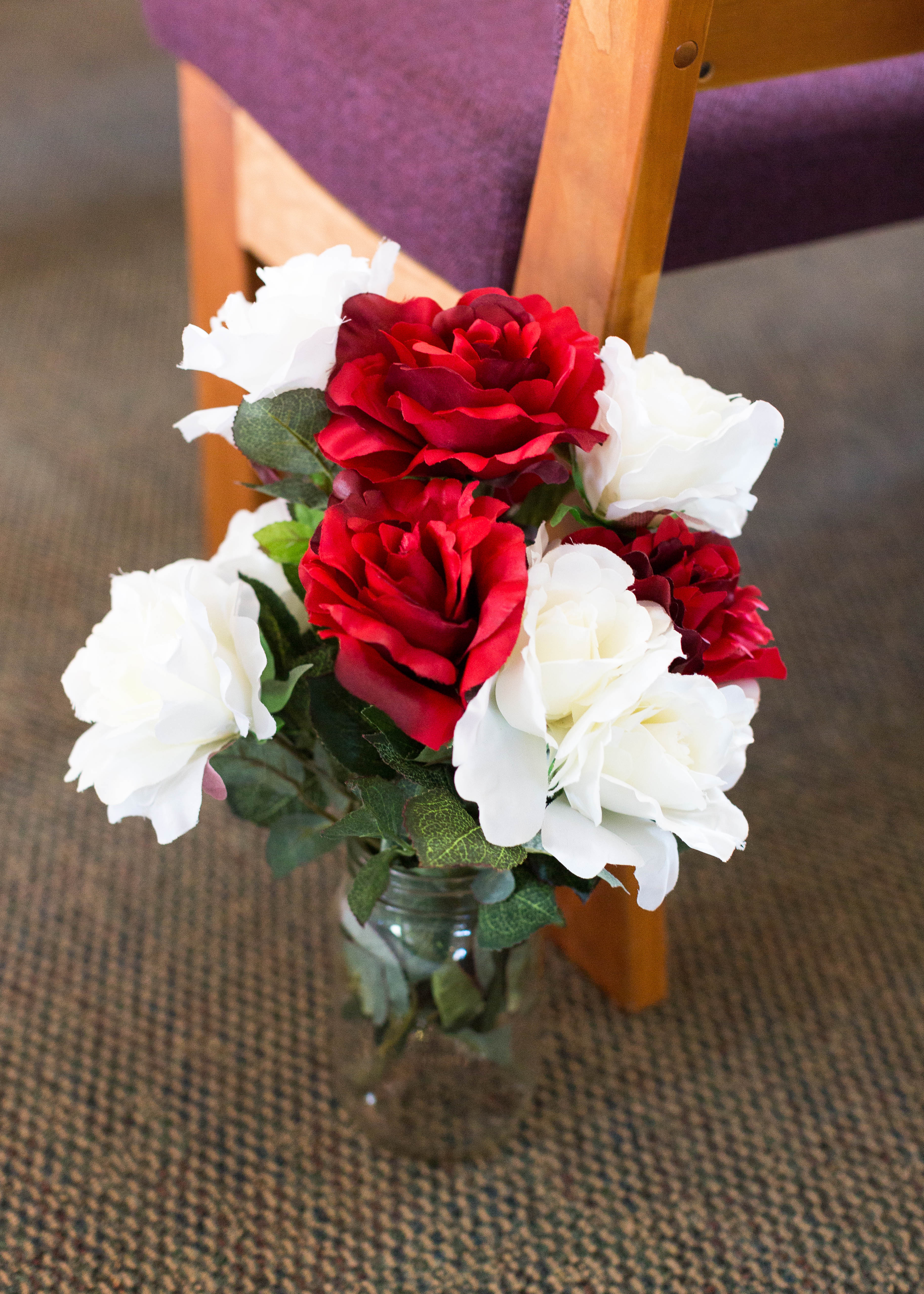 glass vase filled with white a red fabric roses