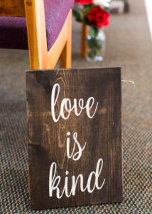rustic wooden sign with the words "love is Kind" written on it
