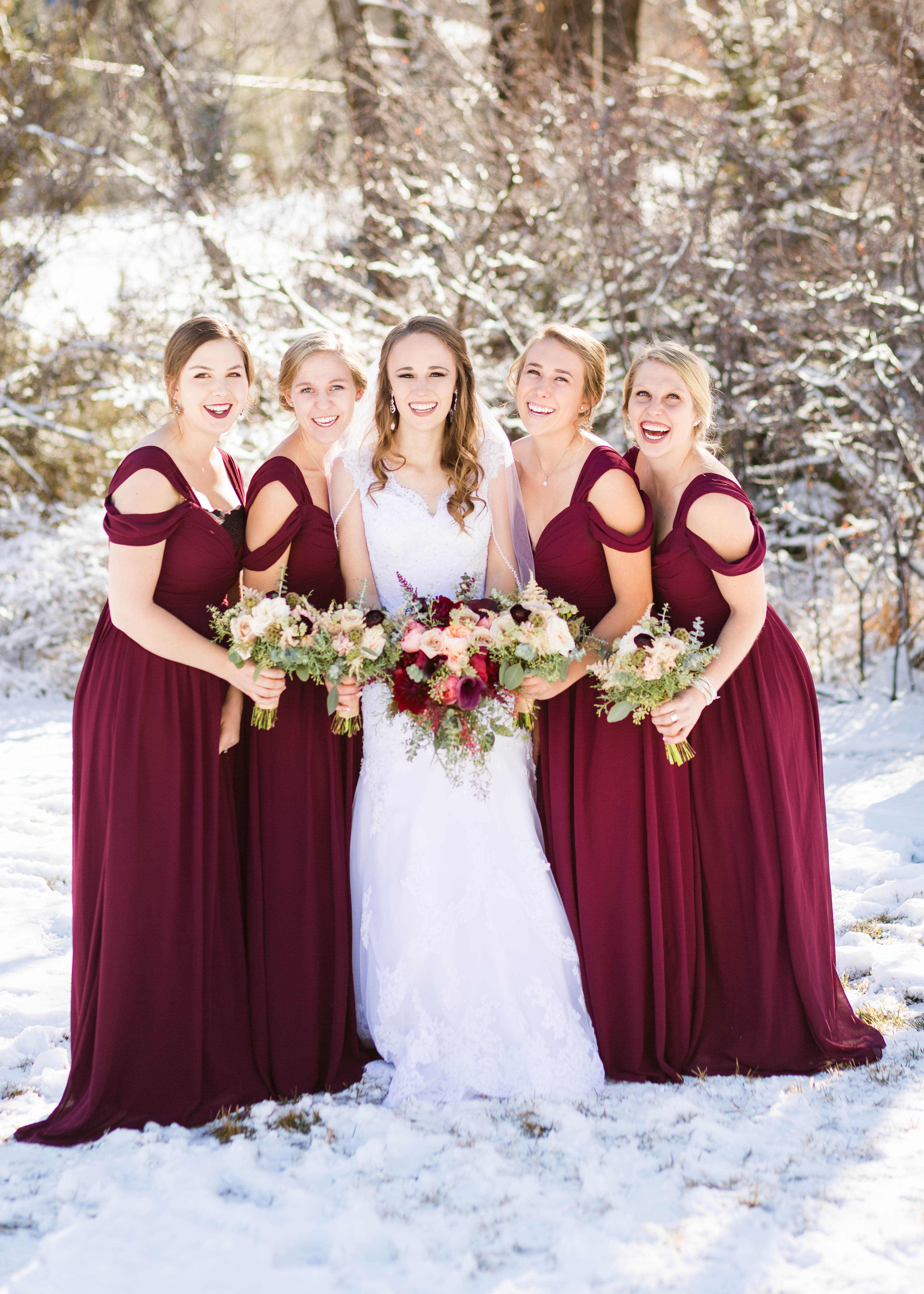 bride is surrounded by her bridesmaids in the snow