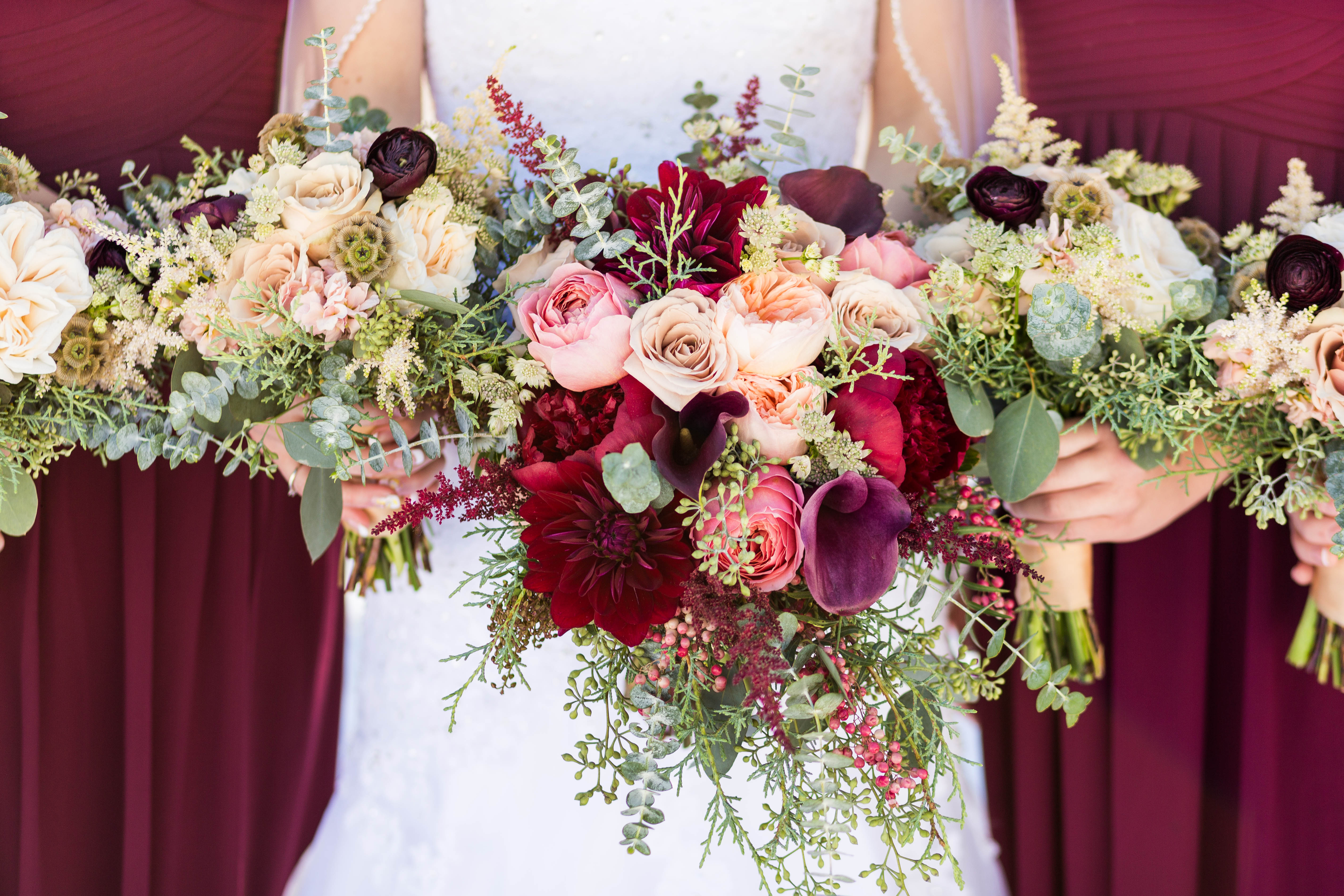 closeup of bride's and bridemaids' burgundy and pink bouquets filled with Dahlias and garden roses