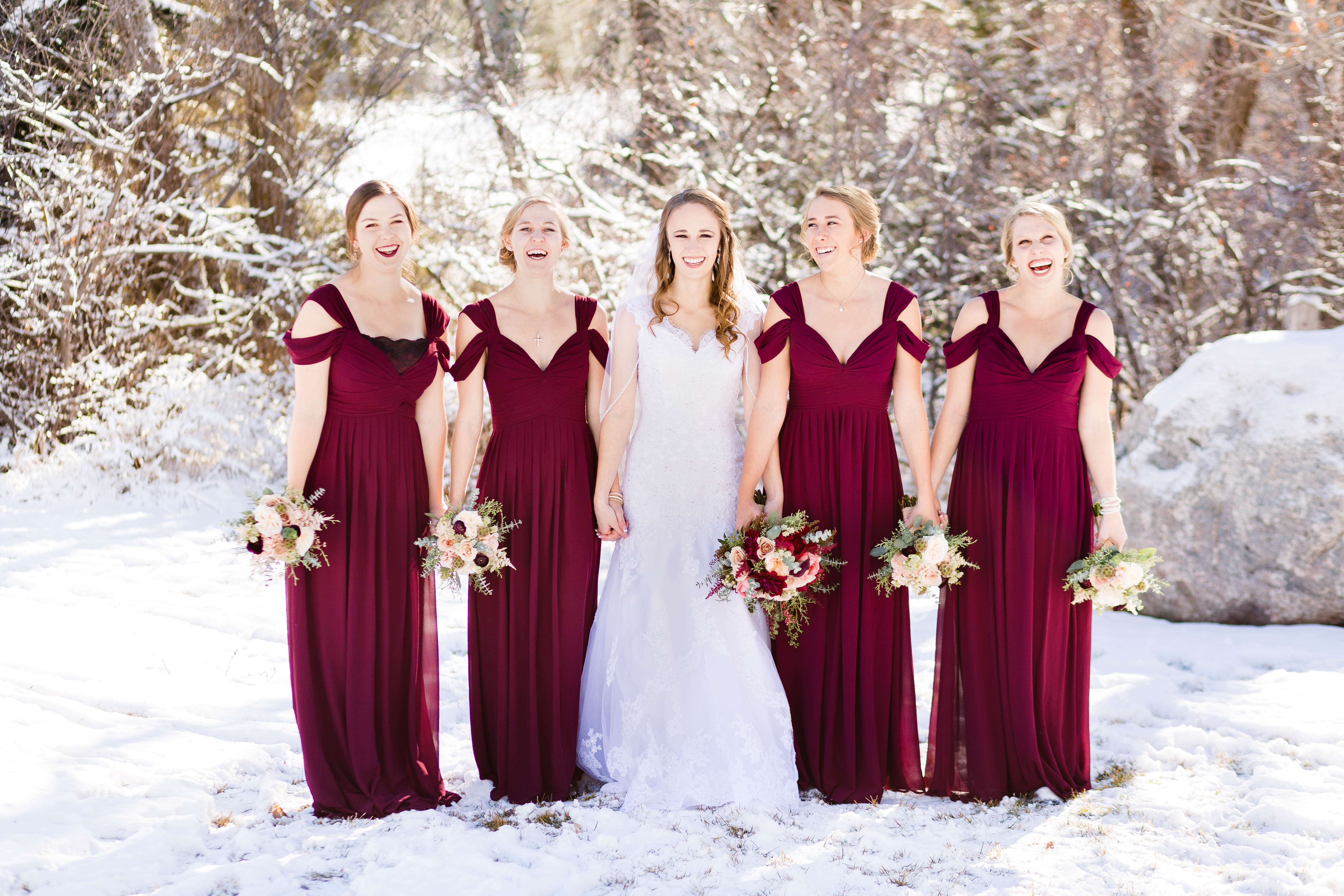 bride laughs with her bridesmaids in the snow