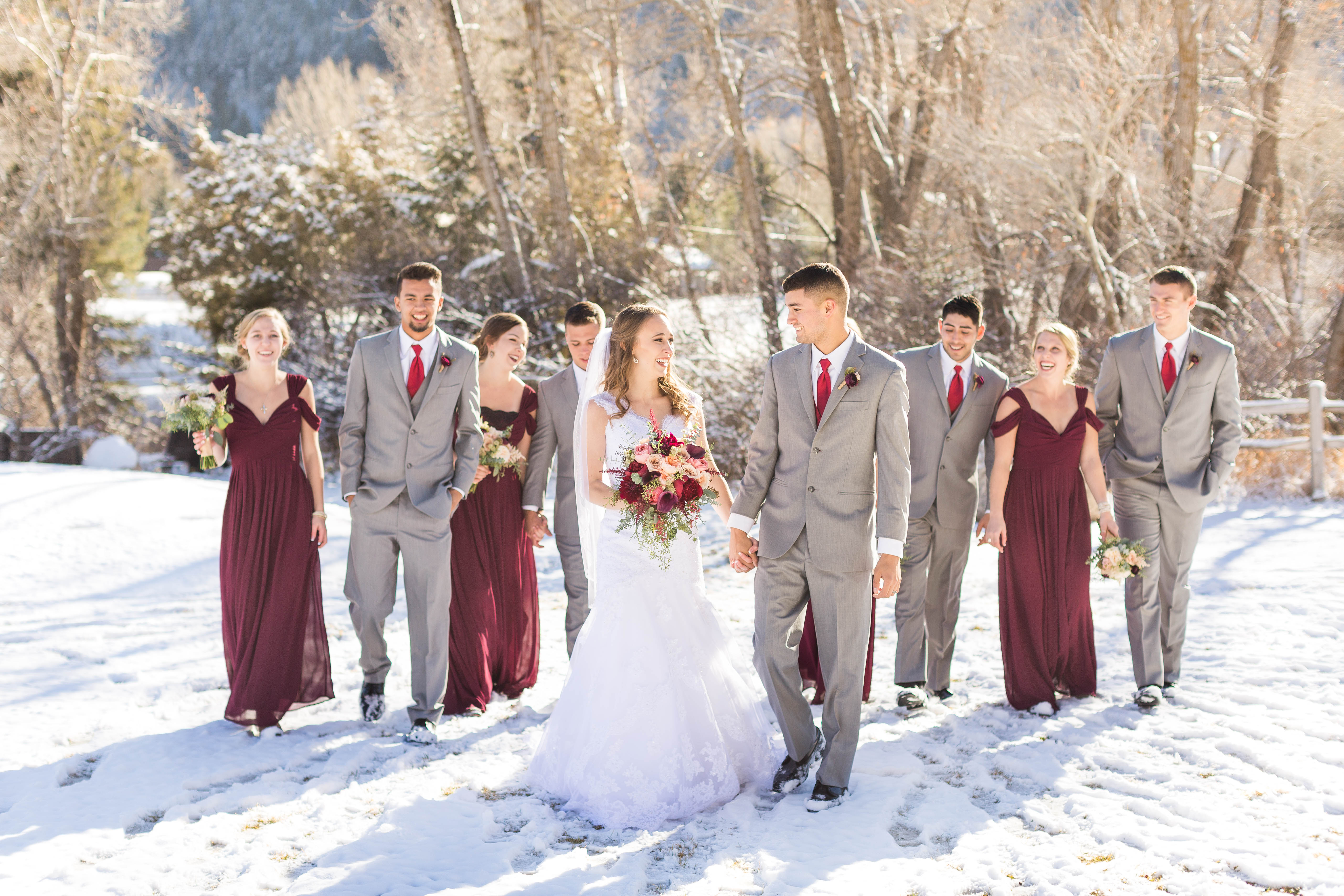 couple walks through the snow with their wedding party