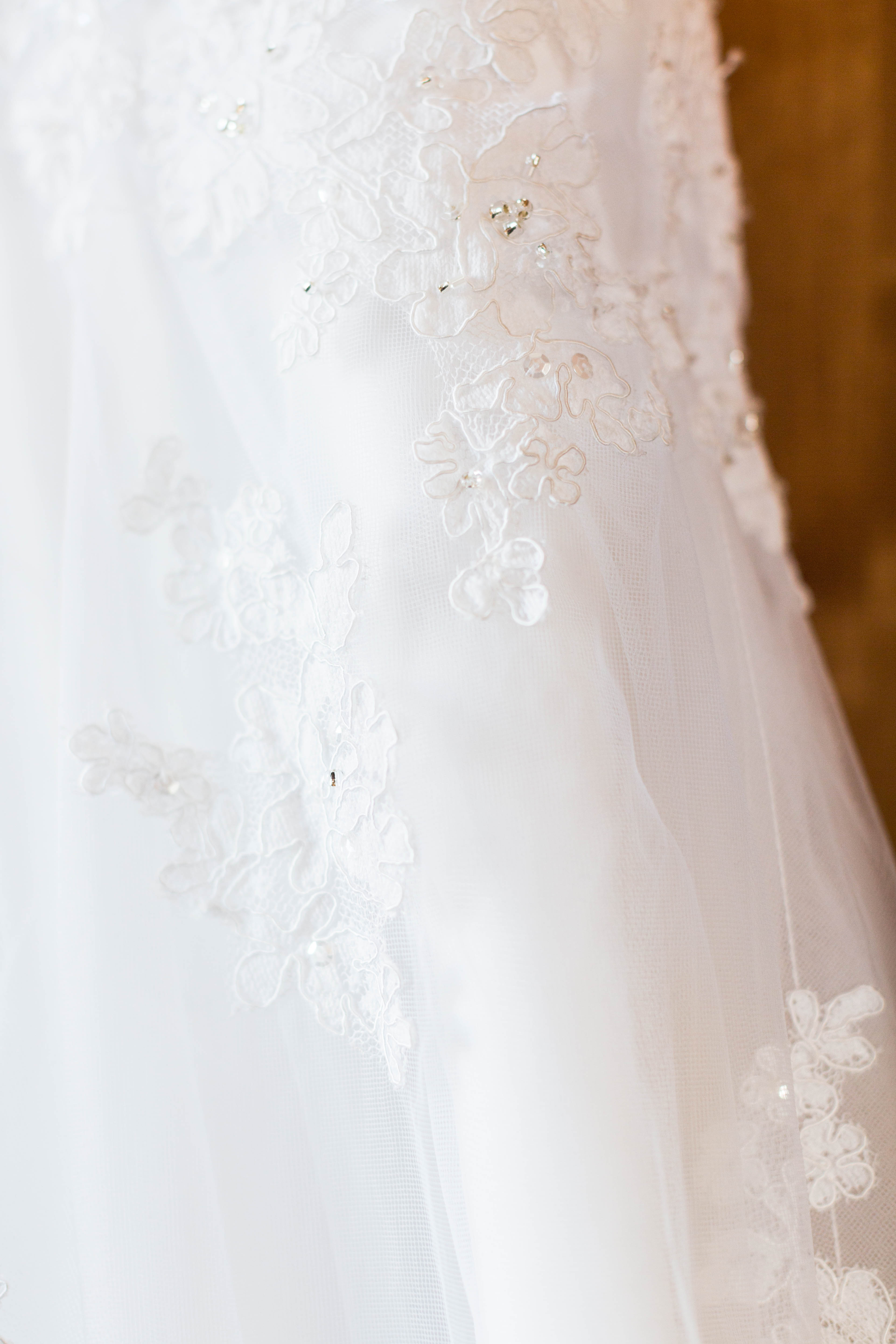 closeup of crystal beading on a white lace wedding dress