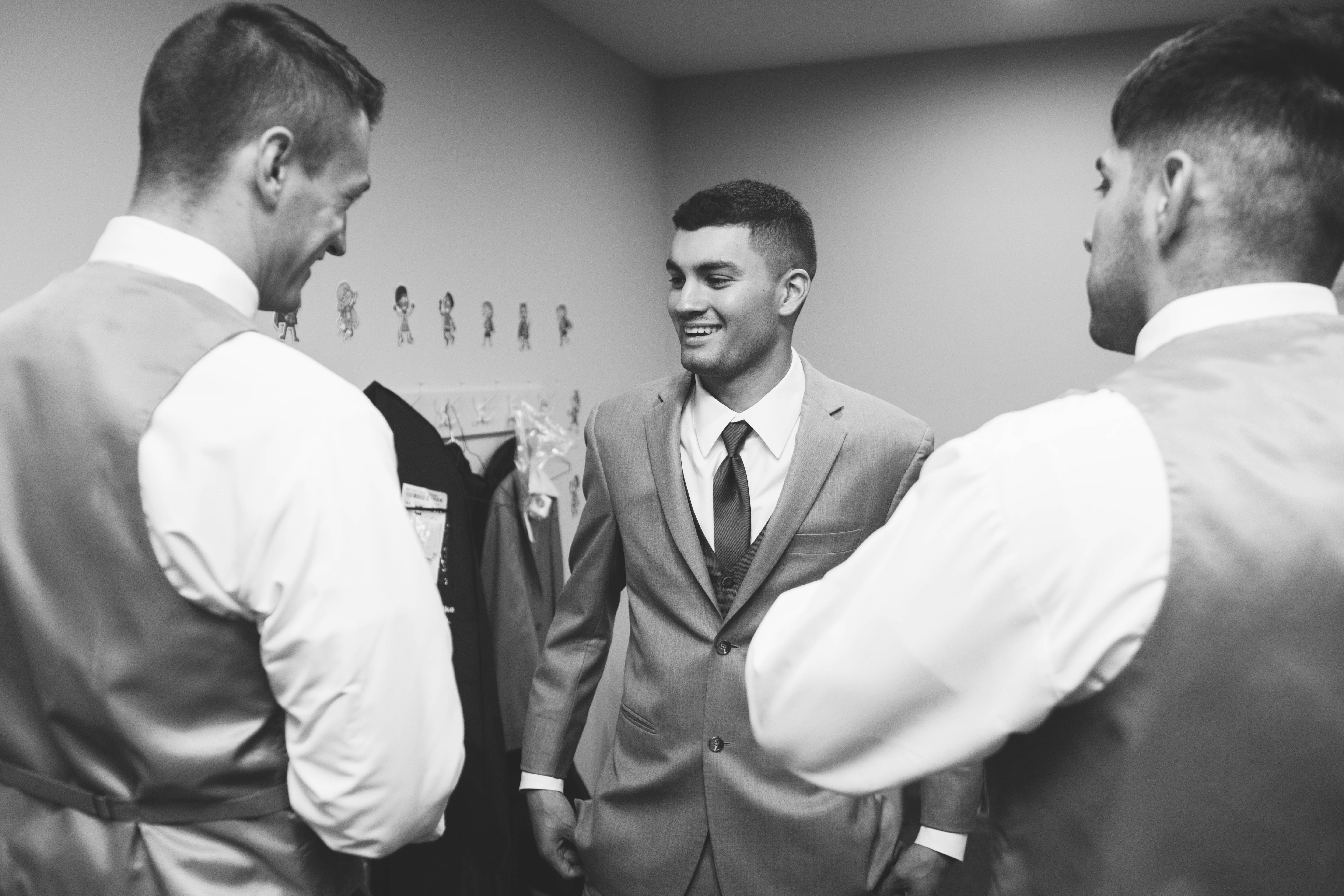 Groom laughs with groomsmen while getting ready