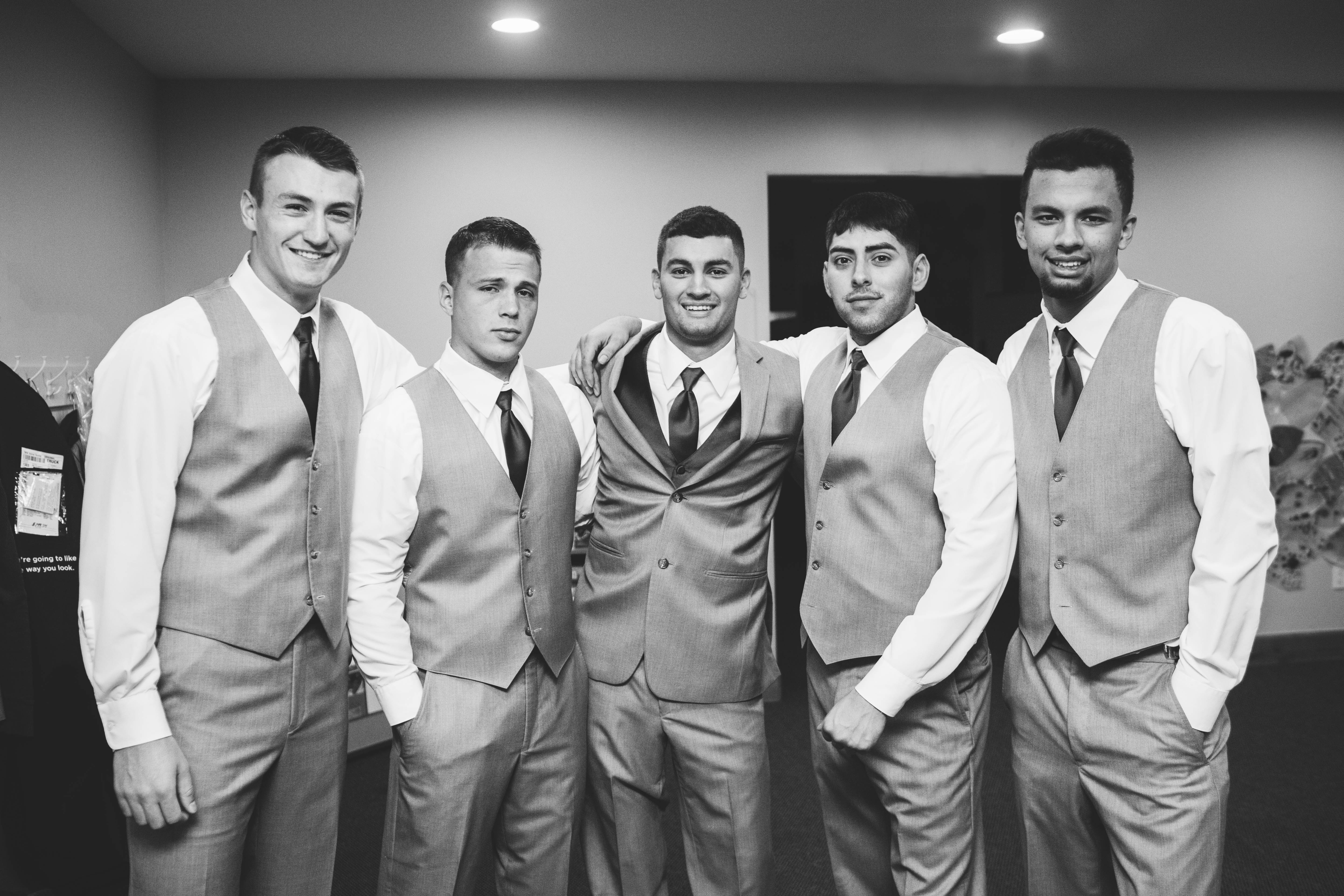 groom poses with groomsmen for a photo while getting ready