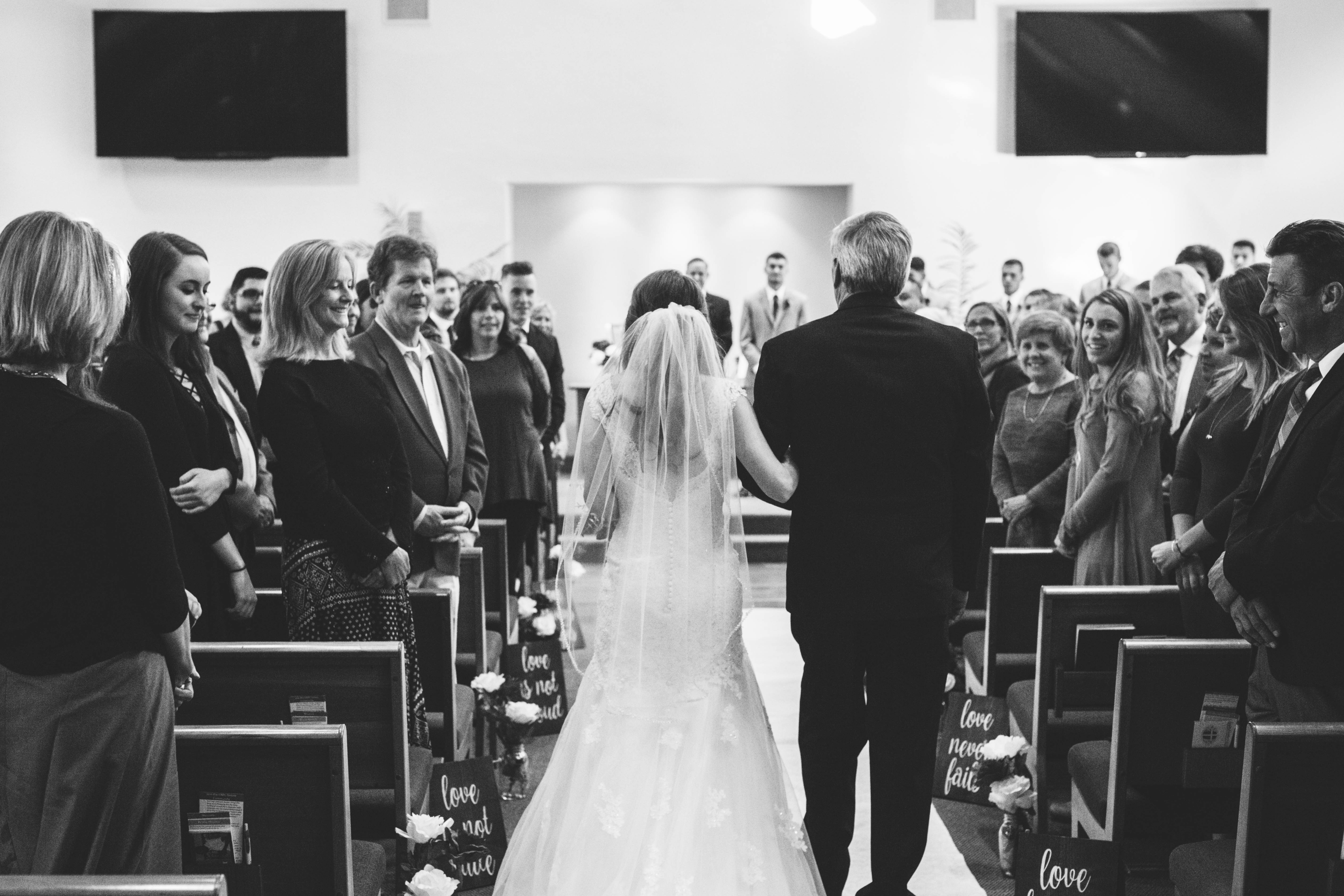 bride holds her dad's arm as she walks down the aisle
